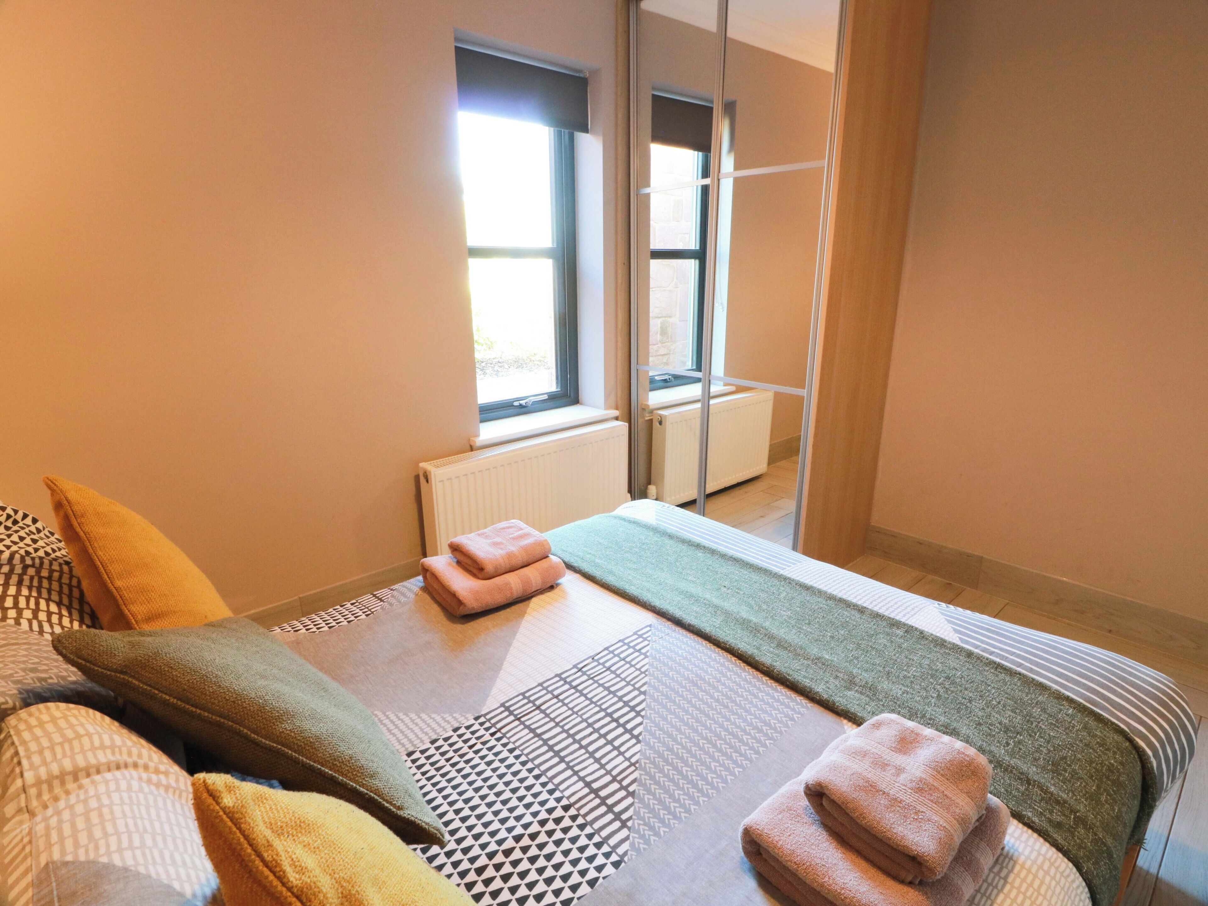 A bedroom with a bed, pillows, a window, and a radiator.