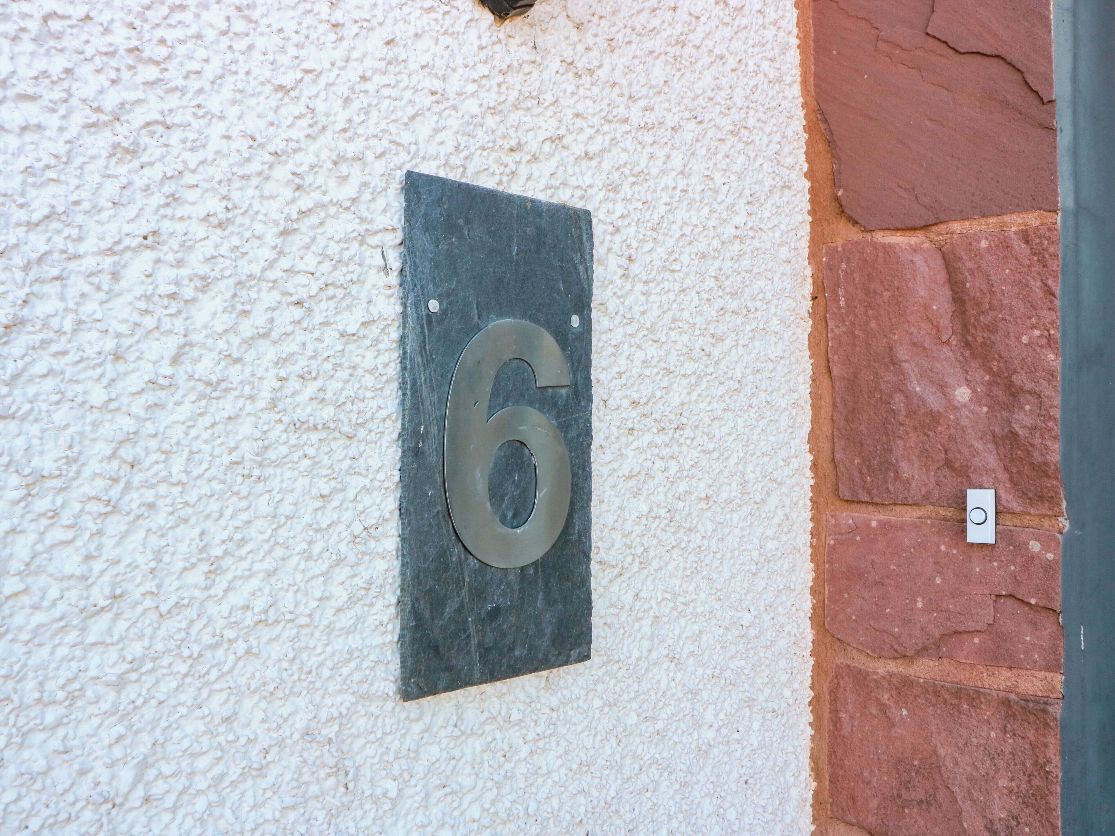 A house number plaque on a textured wall.