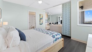 Un dormitorio con cama, ventilador de techo, ventana con vistas y baño con ducha.