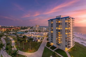 A high-rise hotel with multiple balconies, a pool, and a view of the beach at sunset. - Estero Beach & Tennis 908-b (Fort Myers Beach)