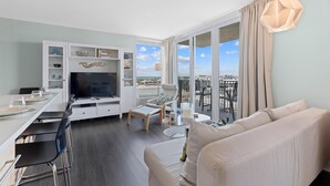 Una sala de estar moderna con televisor, sofá, mesa de comedor y sillas.