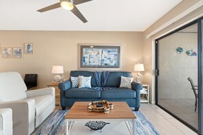 A living room with a sofa, coffee table, and a ceiling fan. - Carlos Pointe #523-shelloway (Fort Myers Beach)
