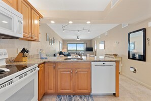 A modern kitchen with wooden cabinets, a built-in microwave, and a dishwasher. - Carlos Pointe #523-shelloway (Fort Myers Beach)