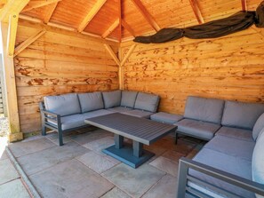 Eine Holzhütte mit Steinboden, einer Bank und einem Sofa.