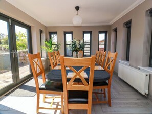 Un comedor con mesa y sillas, ventanas amplias y vista al exterior.