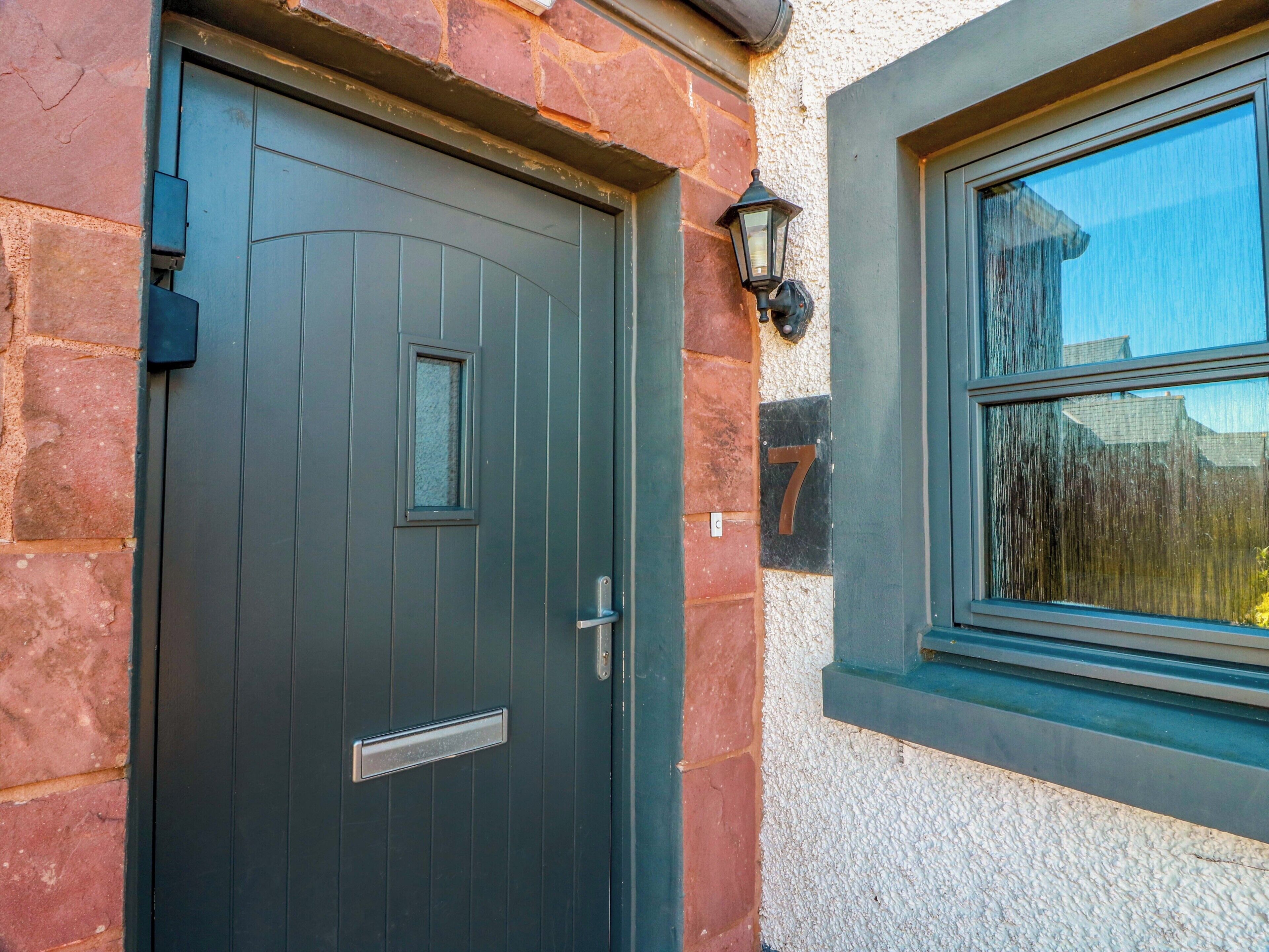 A dark-colored door with a small window and a doorbell.