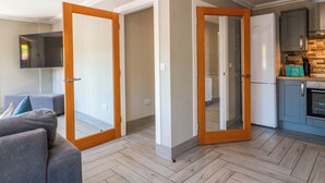 A modern apartment with a living room, kitchen, and a hallway leading to a bedroom. - Ballaganlea (Alexandria)