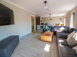 Ein Wohnzimmer mit einer Couch, einem Couchtisch und einem an der Wand befestigten Fernseher.