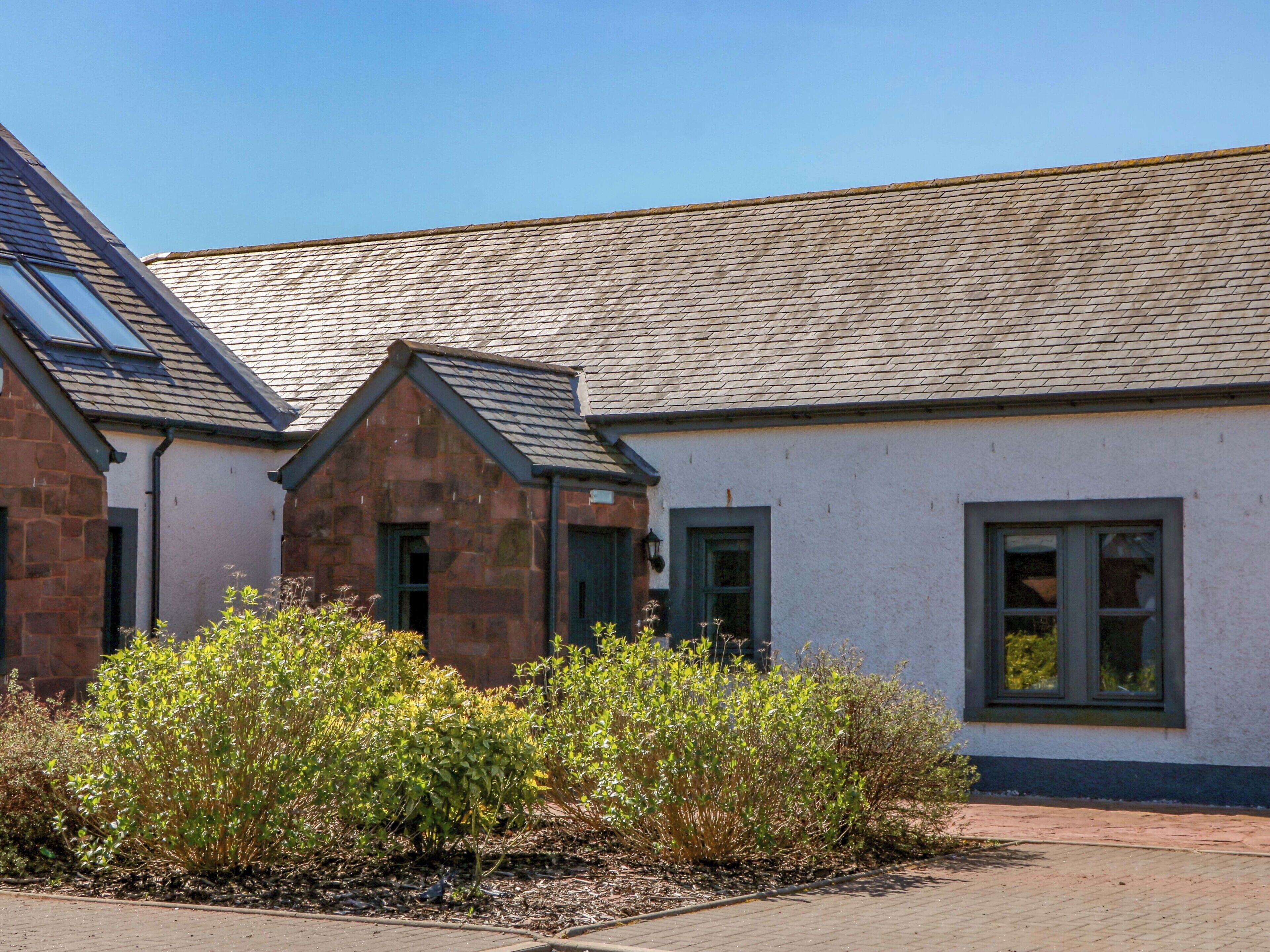 A building with a sloped roof, stone walls, and a paved walkway.