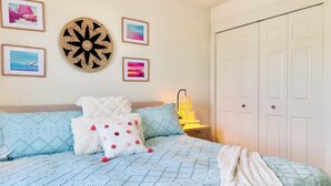 Un dormitorio con cama, almohadas, una lámpara y cuadros en la pared.