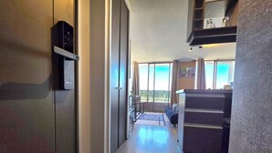 A hallway with a wooden floor, a sliding door, and a kitchen area with a counter and cabinets. - Hermoso Departamento Estación Central (Santiago)