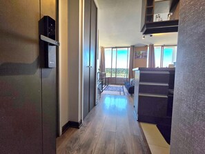 A hallway with a wooden floor, a sliding door, and a kitchen area with a counter and cabinets.