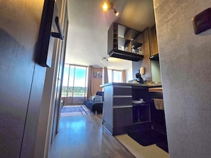 Una cocina moderna con una isla integrada, un área de comedor con sofá y un amplio ventanal corredera que da a un balcón.