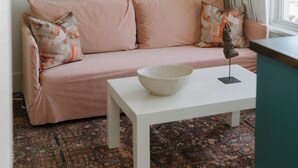 Un salón con sofá, una mesa, un cuenco y una obra de arte en la pared.
