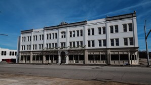 Un edificio de varios pisos con una entrada central, ventanas amplias y fachada plana.