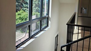 Eine Treppe führt zu einer zweiten Etage mit einem großen Fenster mit Blick auf Grünflächen.