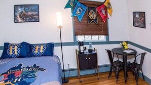 A room with a bed, a bedside table, a chair, a small table with a vase, and a window with blinds. - The Rowling at The Manor on  Rosedale Bed & Breakfast  (Highspire)