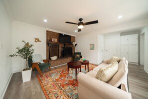 A living room with a fireplace, a ceiling fan, and a sofa. - Spacious 3BR Retreat~ Weddings, Crews & Families (Little Rock)