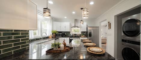 A modern kitchen with a central island, stainless steel appliances, and pendant lighting.