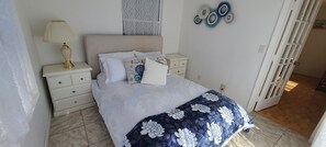 A bedroom with a bed, bedside tables, a lamp, and decorative wall art.