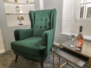 A green armchair, a small table with a bottle and glasses, and a window with a view. - 47 Baxtergate (Whitby)