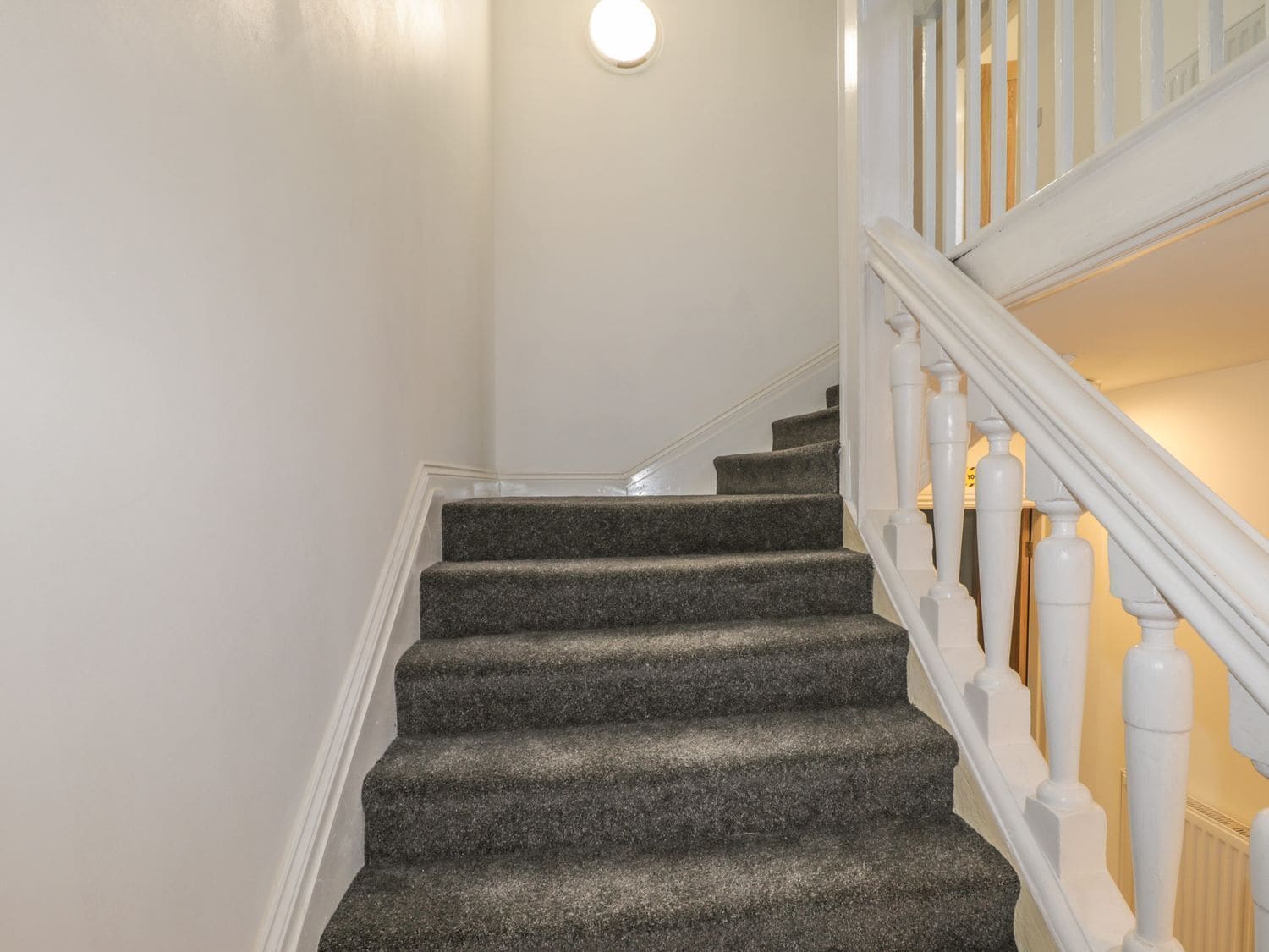A staircase with carpeted steps and white balusters.
