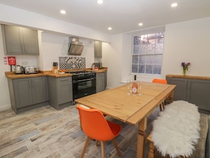 Una cocina moderna con gabinetes grises, una mesa de madera y sillas naranjas.