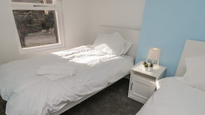 Une chambre à coucher avec un lit, une table de chevet avec une lampe et une fenêtre.