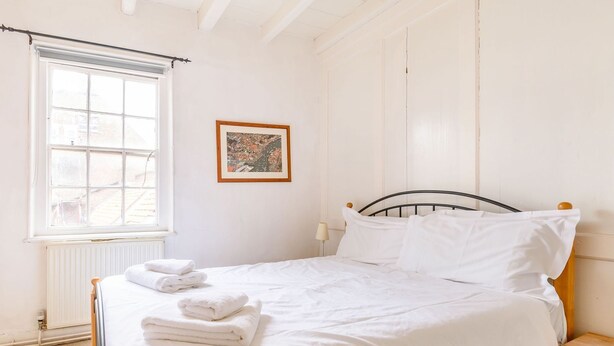 A bedroom with a bed, a window, a radiator, and a framed picture on the wall. - The Anchorage (Whitby)