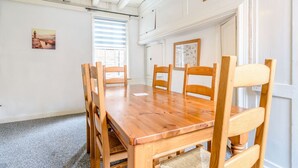 A dining area with a wooden table and chairs, a window with blinds, and a ceiling light fixture. - The Anchorage (Whitby)