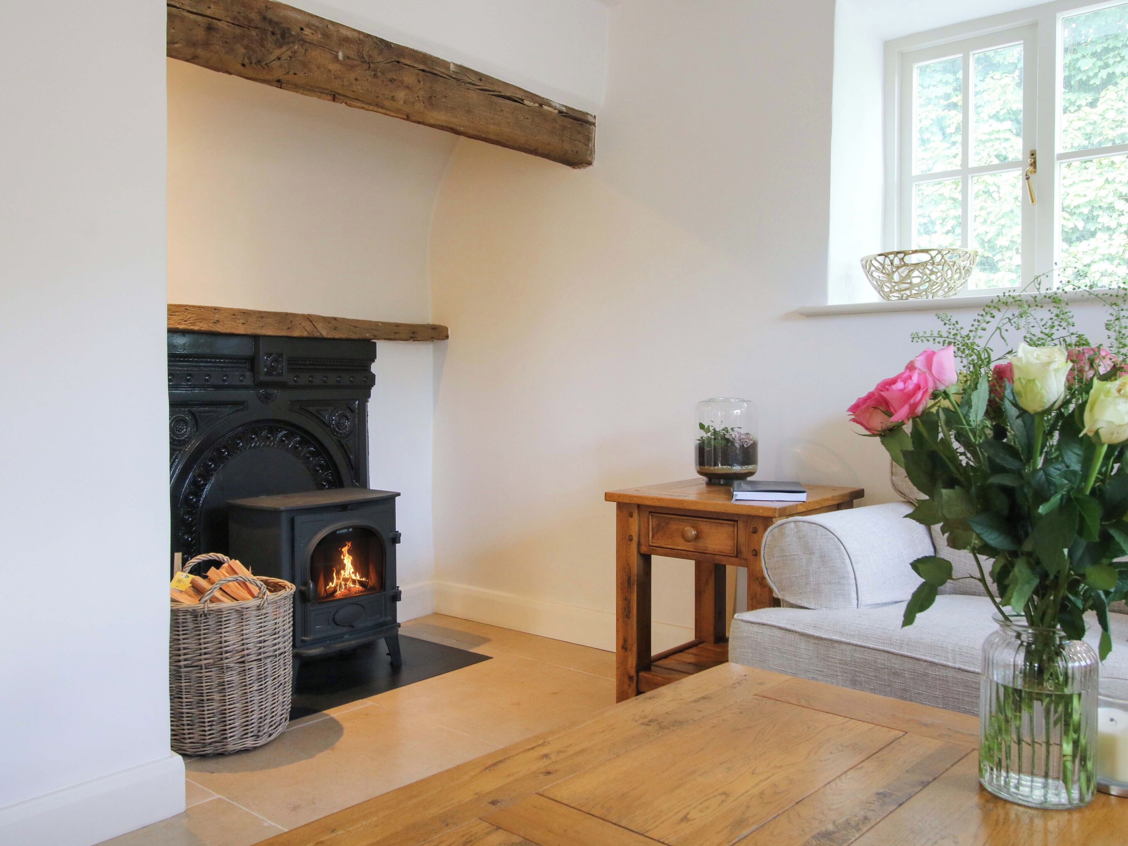 A cozy room with a fireplace, a wooden table, a sofa, and a vase of flowers.