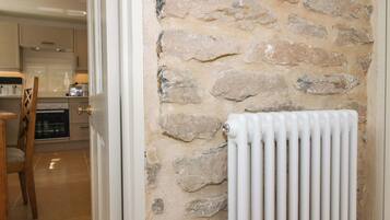 A kitchen with a stone wall, a radiator, and a wooden chair.