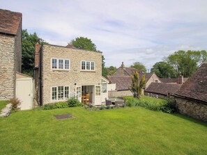 Une maison en pierre à deux étages, avec une porte d’entrée et un petit jardin.