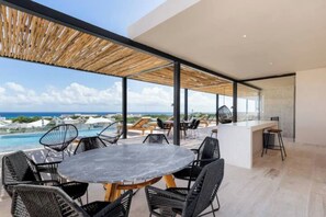 A modern outdoor dining area with a view of the ocean and a pool. - Playa del Carmen Studio|Steps away from the Ferry+Rooftop (Playa del Carmen)