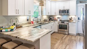 Eine moderne Küche mit weißen Schränken, einer Granit-Arbeitsplatte, Edelstahlgeräten und einem eingebauten Backofen.