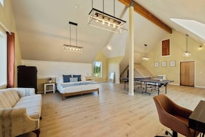 A spacious loft bedroom with a large bed, a desk, and a dining table.