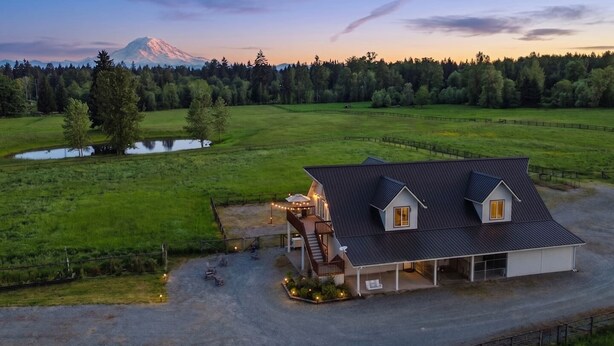 Une maison avec un grand garage, une véranda et une vue sur une montagne.
