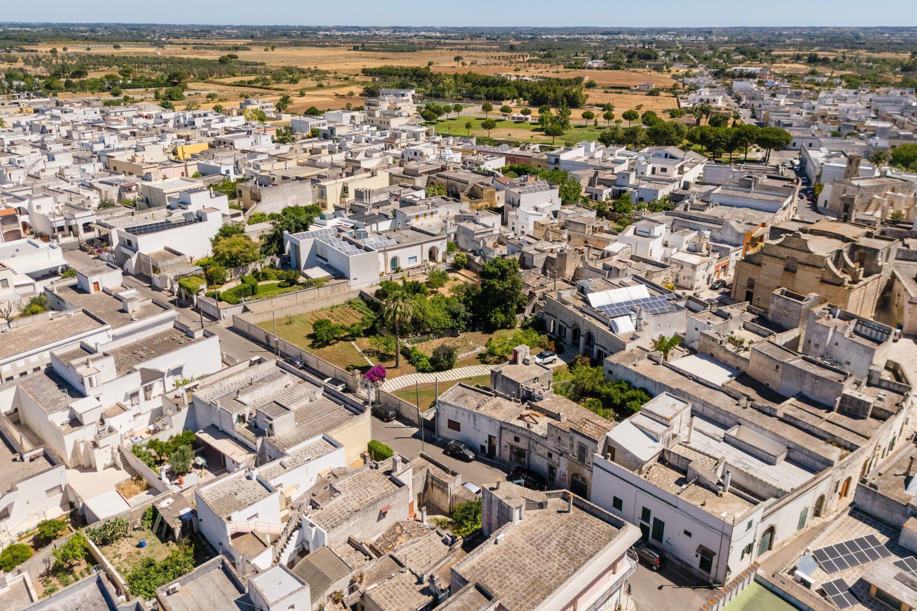An aerial view of a densely packed urban area with numerous buildings, narrow streets, and some greenery.