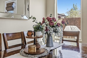 Une table à manger ornée d’un vase de fleurs, d’un panier en osier et d’un plateau en bois.