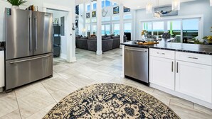 Een moderne keuken met roestvrijstalen apparatuur, een eetgedeelte met uitzicht en een woonruimte met een bank.