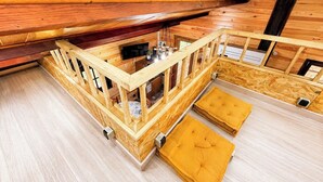 An attic room with wooden walls, a wooden staircase, and a small seating area. - Nature & relaxation chalet near the Loire Castles (Rilly-sur-Loire)