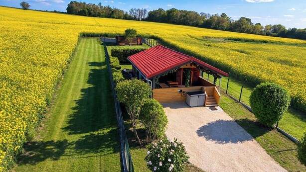 A rural property with a red-roofed cabin, a gravel driveway, and a field of yellow flowers. - Nature & relaxation chalet near the Loire Castles (Rilly-sur-Loire)