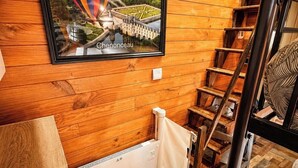 A wooden interior with a framed picture of a hot air balloon over a bridge, a wooden staircase, and a radiator. - Nature & relaxation chalet near the Loire Castles (Rilly-sur-Loire)