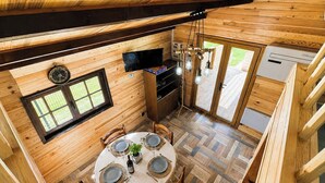 A wooden cabin with a dining area, a television, and a small kitchen. - Nature & relaxation chalet near the Loire Castles (Rilly-sur-Loire)