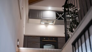 A kitchen with grey cabinets, a built-in oven, and a stainless steel range hood. - Historic Stone House on Vir Island (Vir)