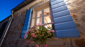 A stone building with a window and shutters, a hanging flower basket, and a clear blue sky. - Historic Stone House on Vir Island (Vir)