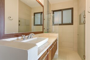 Een badkamer met een dubbele wastafel, een douche en een douchecabine met glazen wanden.