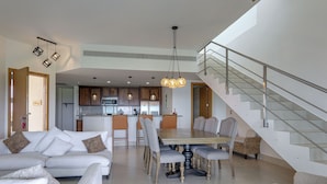 Un salon moderne comprenant un coin repas, une cuisine et un escalier.