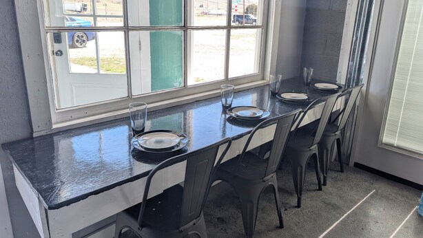 Un espace repas comprenant une longue table, des chaises et une fenêtre donnant sur l’extérieur.
