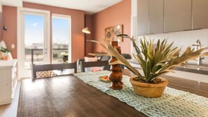 Un coin repas avec une table en bois, une plante en pot et une vue à travers une porte vitrée.